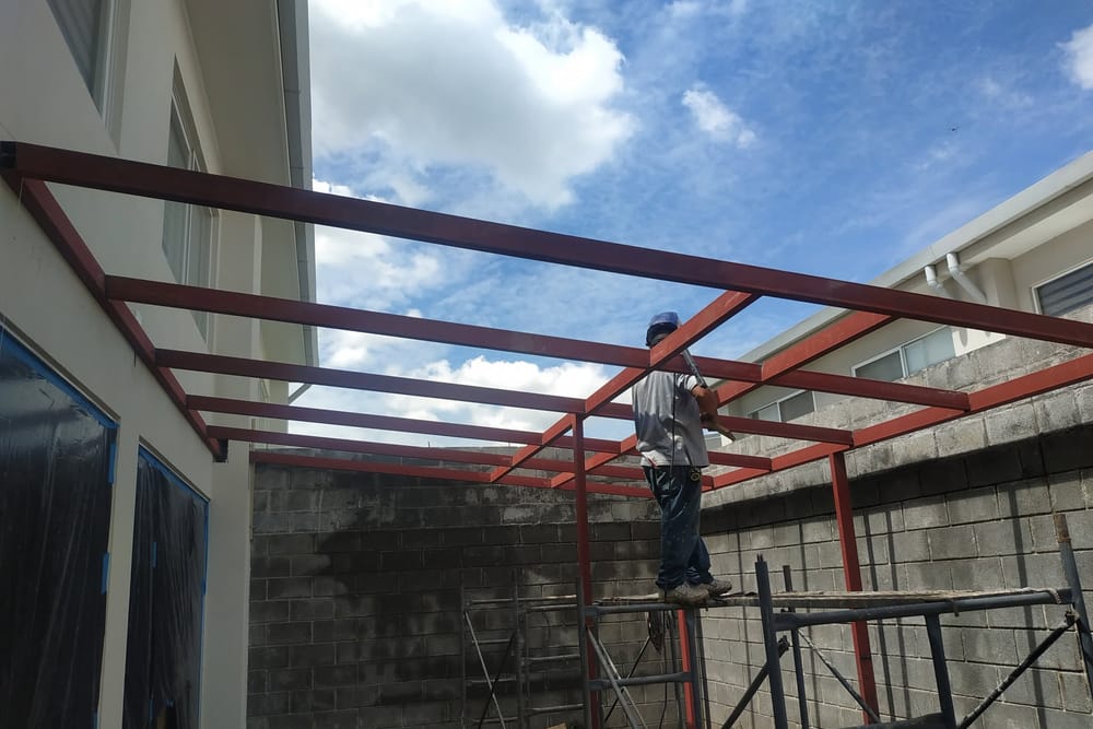 Soldador trabajando sobre andamio en la estructura de un techado